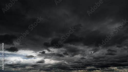 dark dramatic sky with black stormy clouds before rain or snow as abstract background, extreme weather, the sun shines through the clouds, high contrast photo