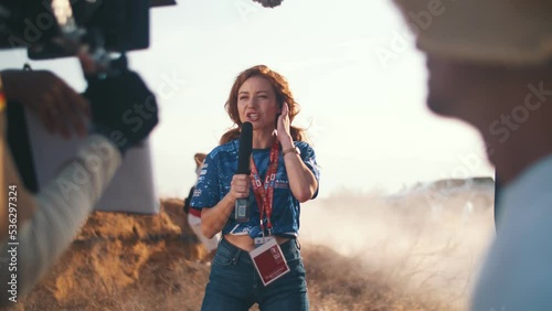 Girl reporter in the field makes a report about the races in the steppe. View from the film crew and prompter. Press works. Movie production