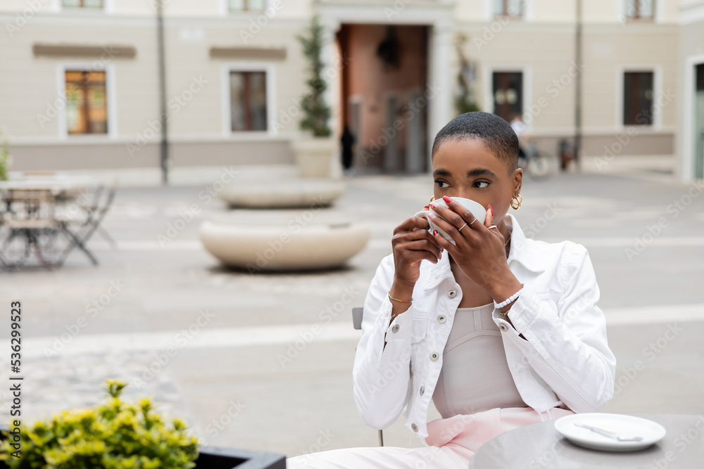 Short haired african american woman drinking coffee in cafe on urban street in Treviso. Short haired african american woman drinking coffee in cafe on urban street in Treviso.