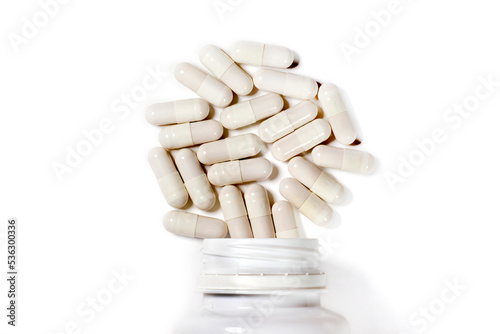 White capsule pills from a plastic bottle on a white background. Epidemic, painkillers, healthcare, medical pills and drug abuse concept. flat laying. Top view