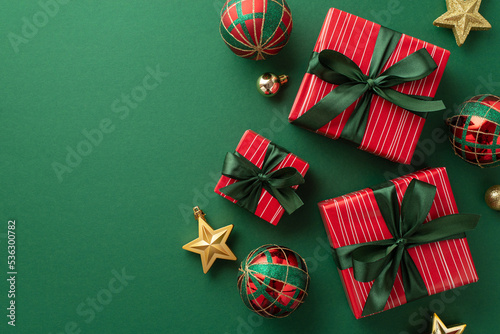 Christmas presents concept. Top view photo of gift boxes with ribbon bows red green gold baubles and star ornaments on isolated green background photo