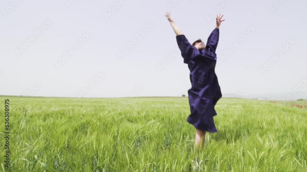 Young man with graduation clothes in a green field throwing hat in the air.. Young man with graduation clothes in a green field throwing hat in the air..