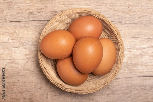 Chicken eggs in bamboo basket on wooden background