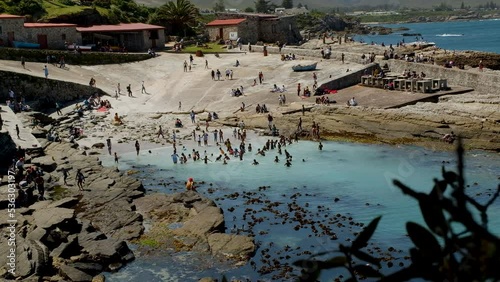 Locals frolicking in clear shallows of beach at Hermanus historic Old Harbour photo