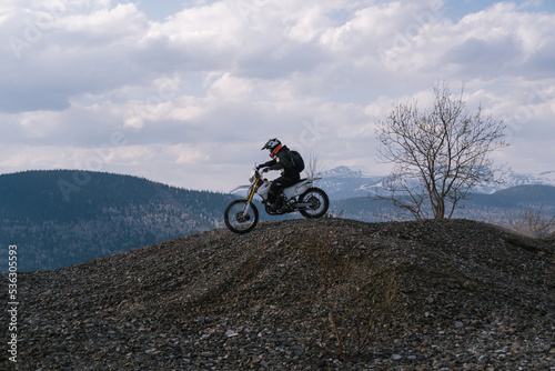 motorcyclist riding off-road dirt motorcycle on gravel hills