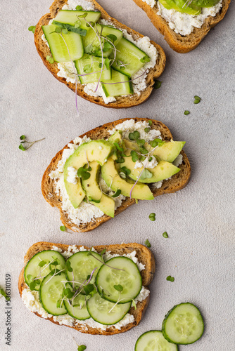 Vegetarian green sandwiches with avocado and cucumber with microgreens on a light background
