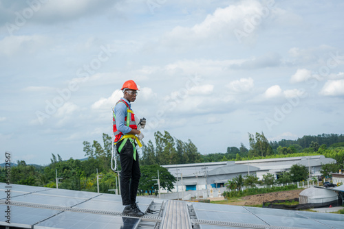 Engineer wearing safety harness belt during working on replacement solar panel in solar power plant,Ecological. © visoot