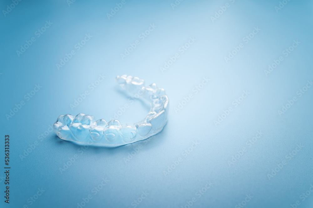 Close up invisible aligners on the blue background with copy space. Plastic braces dentistry retainers to straighten teeth Close up invisible aligners on the blue background with copy space. Plastic braces dentistry retainers to straighten teeth