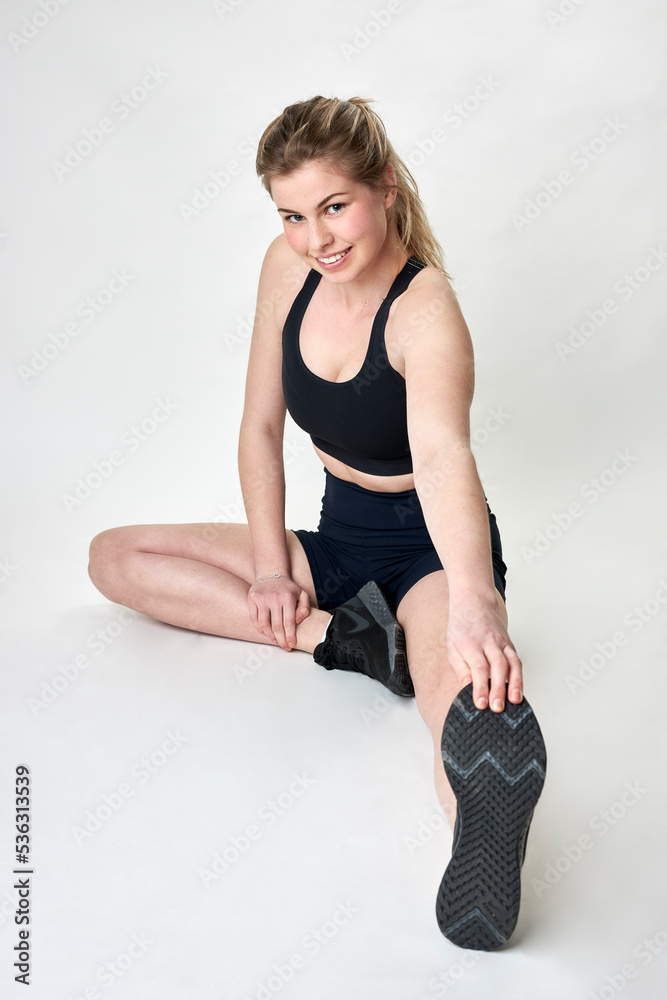 Naklejka premium fit female model stretching on studio floor