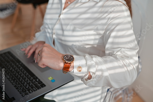 Businesswoman checking the time on her wrist watch, close up.Close up view female freelancer typing on laptop computer.