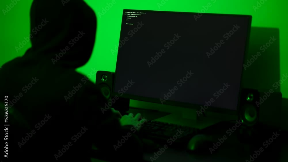 Hacker typing fast on a computer keyboard in a dimly lit room. Medium shot Hacker typing fast on a computer keyboard in a dimly lit room. Medium shot