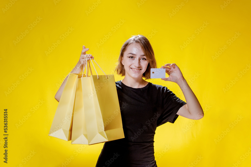 Joyful woman with packages on yellow background, shopping trip. Studio portrait. Black friday sale Joyful woman with packages on yellow background, shopping trip. Studio portrait. Black friday sale