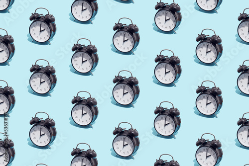 Seamless pattern of black retro alarm clocks  show 2 o'clock. Changing clock from summer time to winter time. Shifting the clock hands back in autumn.
