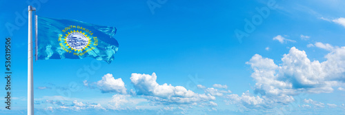 South Dakota - state of USA, flag waving on a blue sky in beautiful clouds - Horizontal banner
 photo