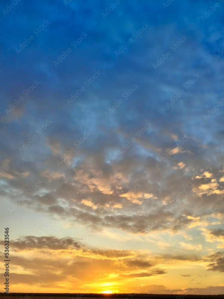 Abstraction of colorful orange and blue clouds in the sky during sunset.