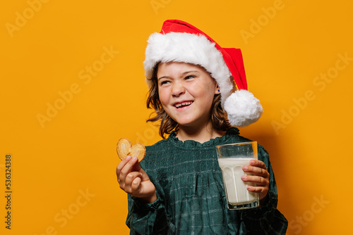 Cheerful girl with cookie and milk for Santa