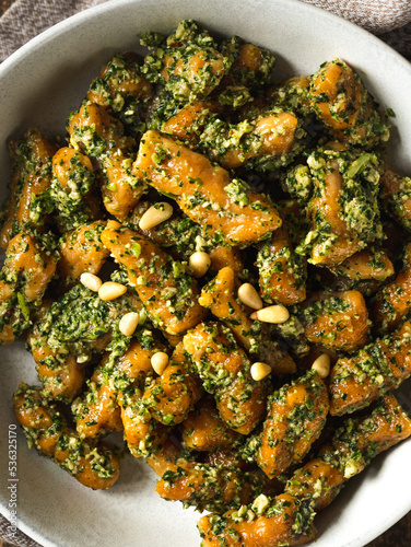 Macro shot of the homemade vegan sweet potato gnocchi with pesto sauce with wild garlic and pine nuts on top, top view 