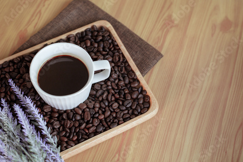 A cup hot coffee with coffee beans on wooden tray