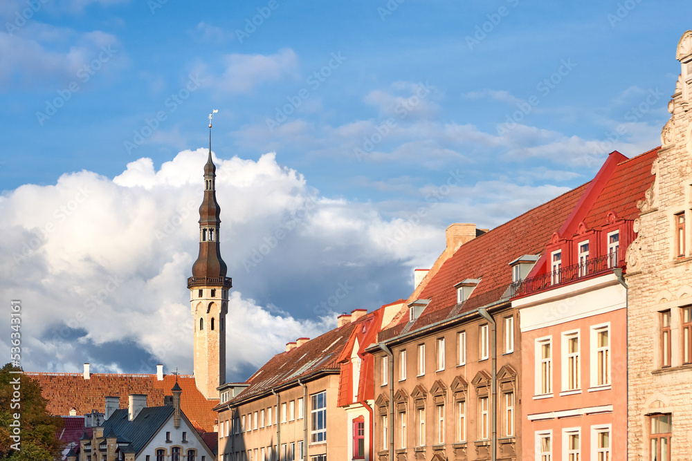 Fototapeta premium Picturesque Tallinn Town Hall tower and close-up on historic facades of ancient medieval buildings. Daytime, blue sky, historical city center of Tallinn, Estonia.