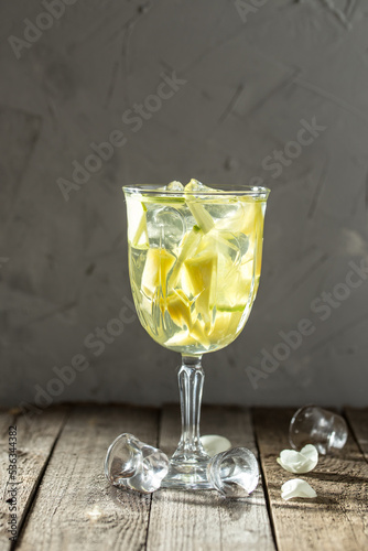 Apple pineapple cocktail with sparkling wine with ice cubes in wine glass on the table