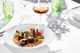 Fregola pasta with seafood and a glass of wine