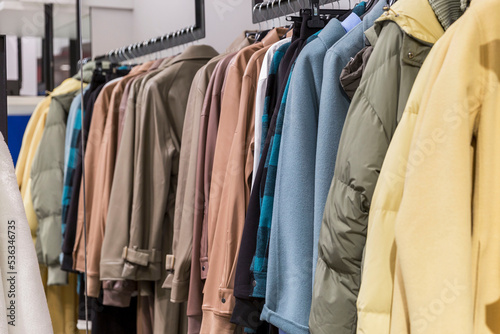 Warm coats in different colors and textures on hangers in the store. New autumn winter collection. Fashion & Style.