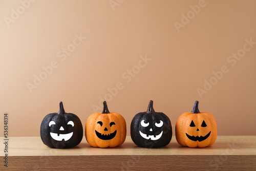 Halloween holiday concept with jack o lantern glitter orange and black pumpkin decoration on wooden table over modern  background