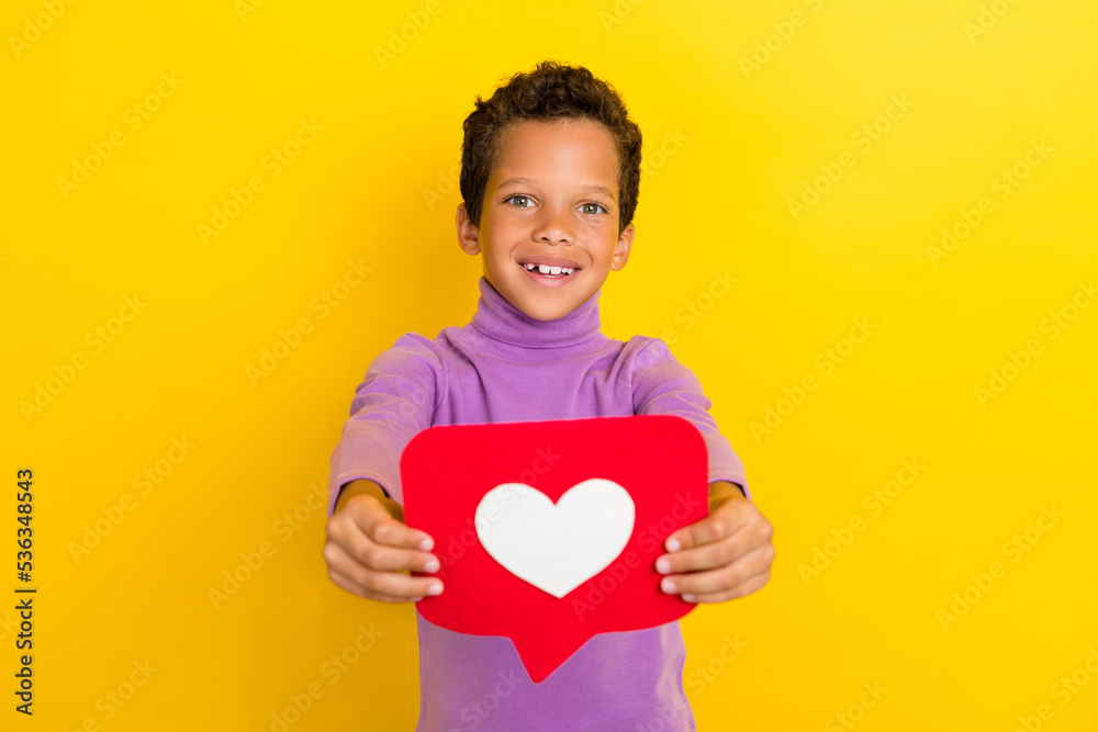 Photo of friendly positive boy arms hold give you paper like card isolated on yellow color background Photo of friendly positive boy arms hold give you paper like card isolated on yellow color background