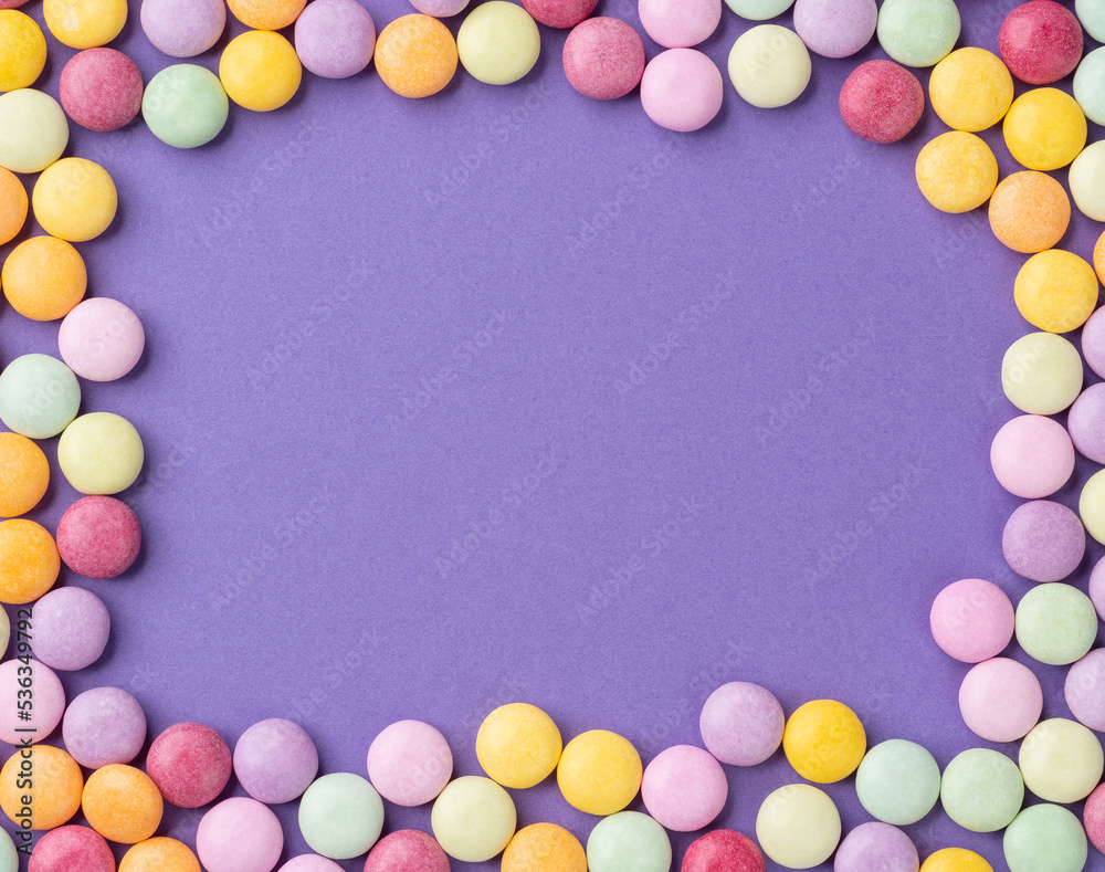 Frame of colorful candies over purple background with copy space Frame of colorful candies over purple background with copy space