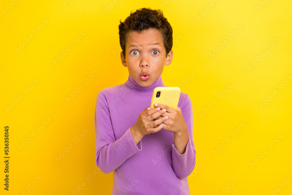 Photo portrait of charming small schoolboy hold gadget impressed news dressed stylish purple look isolated on yellow color background Photo portrait of charming small schoolboy hold gadget impressed news dressed stylish purple look isolated on yellow color background