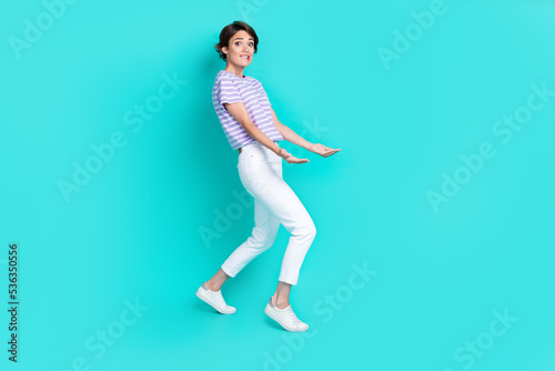 Photo of cute shiny lady wear violet t-shirt carrying arms empty space isolated turquoise color background