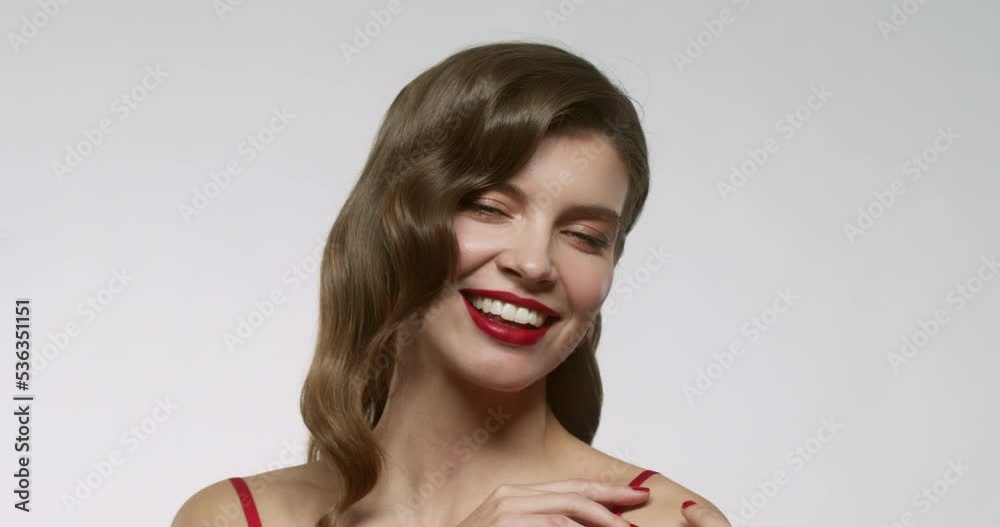 Smiling beautiful woman with red lips posing as female model with evening makeup on the face, isolated on white studio background
