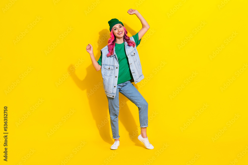 Full length photo of cheerful lucky girl dressed denim vest rising fists isolated yellow color background Full length photo of cheerful lucky girl dressed denim vest rising fists isolated yellow color background