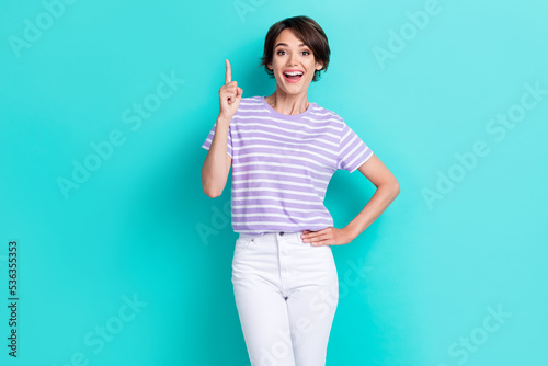 Portrait of adorable positive girl with bob hairdo dressed striped t-shirt showing finger get idea isolated on turquoise color background