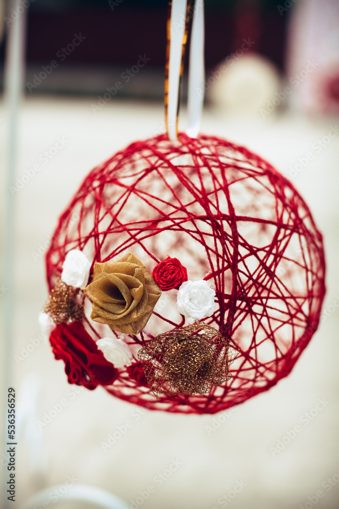 Wedding decor, a red ball glued from threads and flowers in beige, white and red, at a banquet.