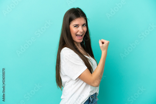Young caucasian woman isolated on blue background celebrating a victory