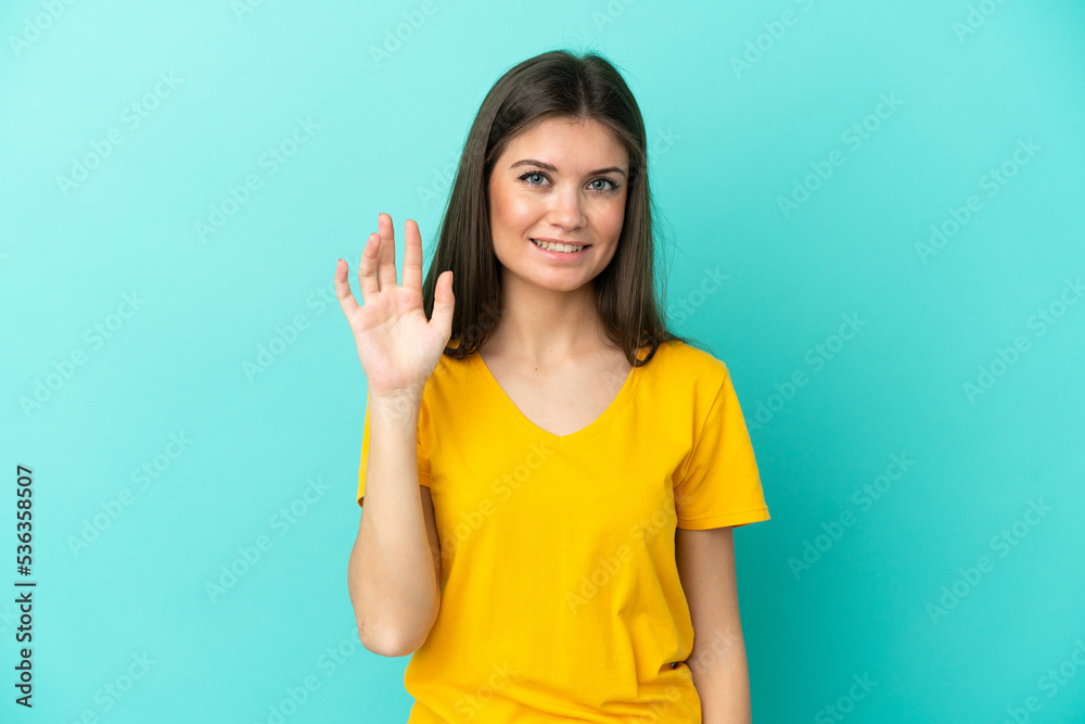 Young caucasian woman isolated on blue background saluting with hand with happy expression Young caucasian woman isolated on blue background saluting with hand with happy expression
