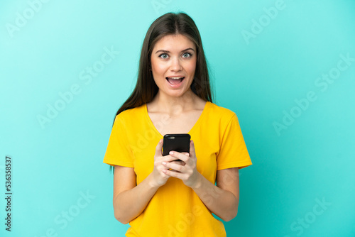 Young caucasian woman isolated on blue background surprised and sending a message