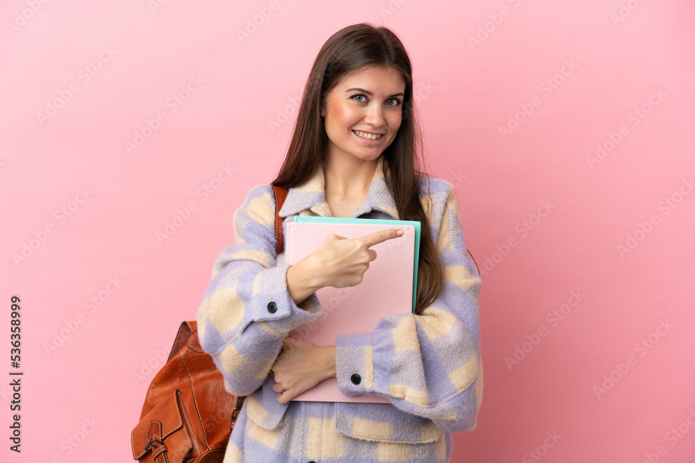 Young student woman isolated on pink background pointing back Young student woman isolated on pink background pointing back