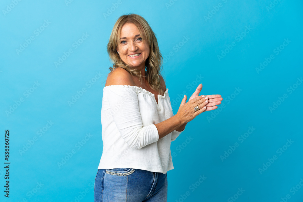 Middle aged blonde woman over isolated background applauding Middle aged blonde woman over isolated background applauding