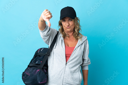 Middle aged sport woman over isolated background showing thumb down with negative expression