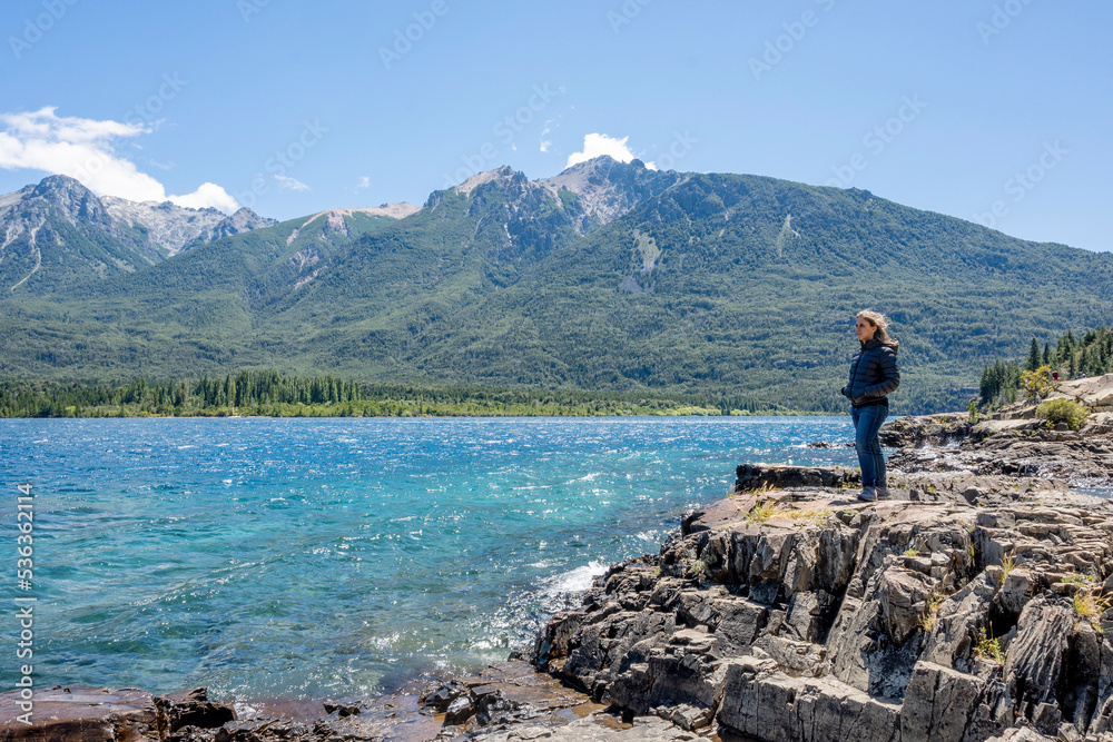 Side view of woman standing on a rock looking at lake