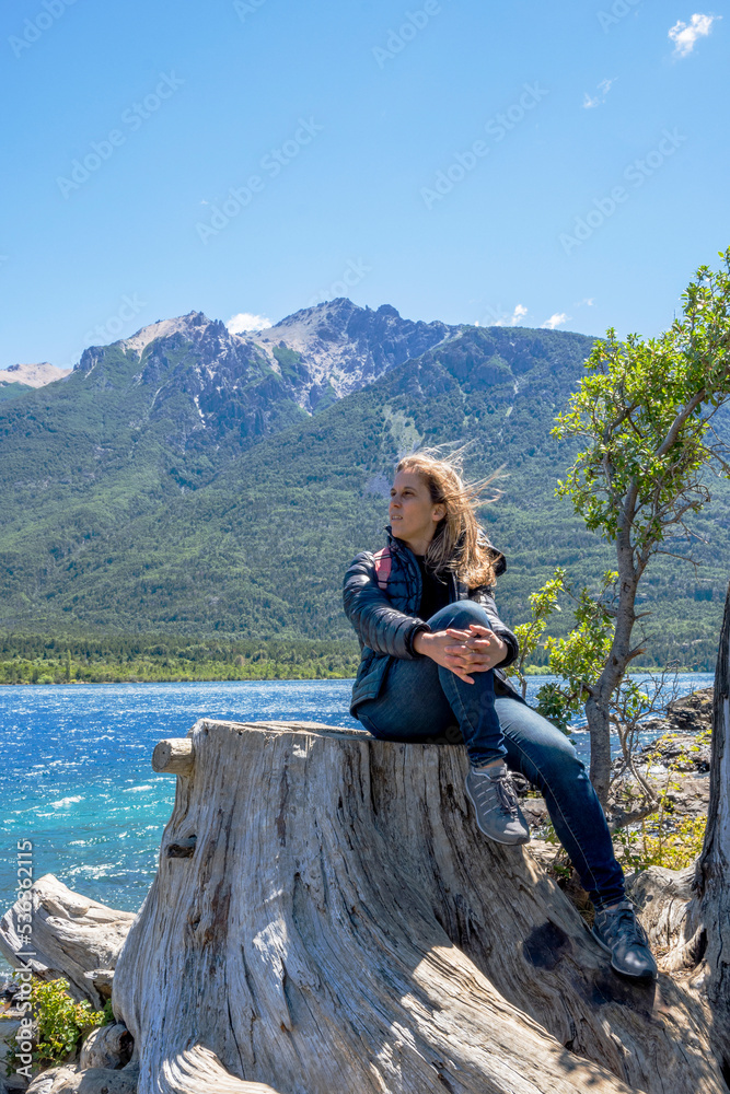 Naklejka premium woman sitting tree stump alone looking out over the lake