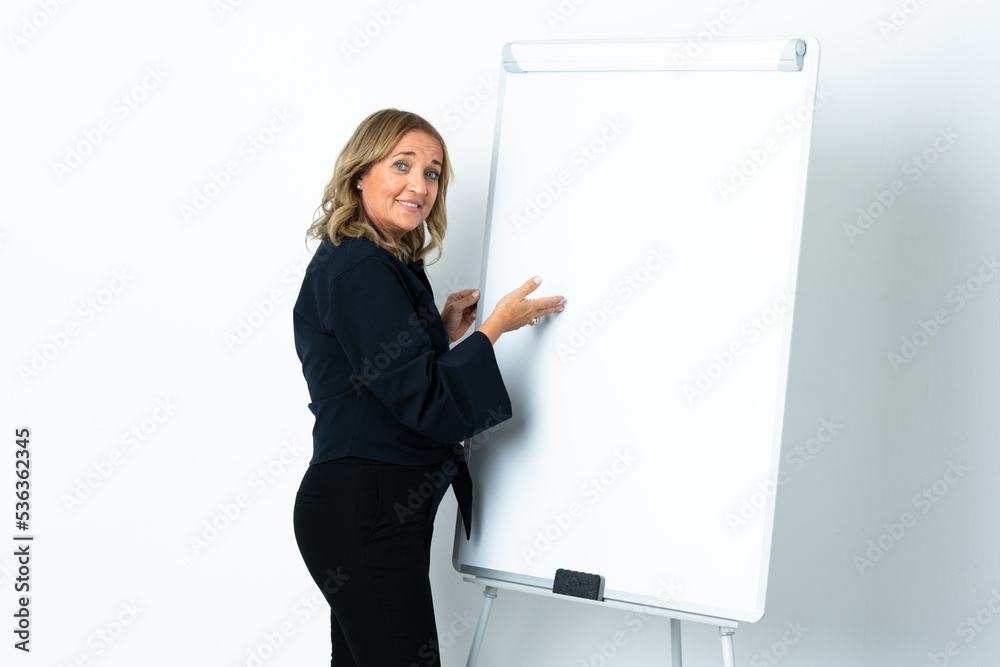 Middle aged blonde woman over isolated white background giving a presentation on white board Middle aged blonde woman over isolated white background giving a presentation on white board