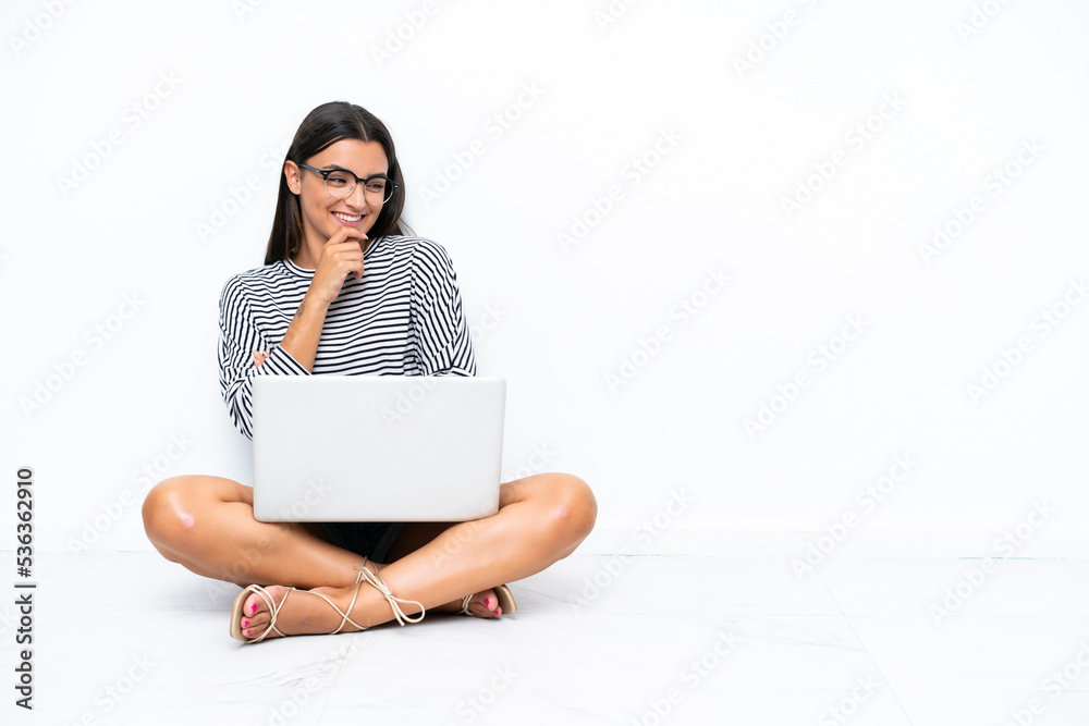 Young caucasian woman with a laptop sitting on the floor looking to the side Young caucasian woman with a laptop sitting on the floor looking to the side