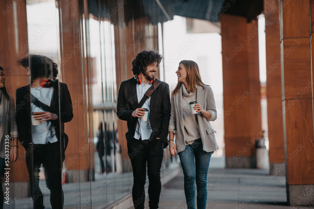 Business man and business woman talking and holding luggage traveling on a business trip, carrying fresh coffee in their hands.Business concept Business man and business woman talking and holding luggage traveling on a business trip, carrying fresh coffee in their hands.Business concept