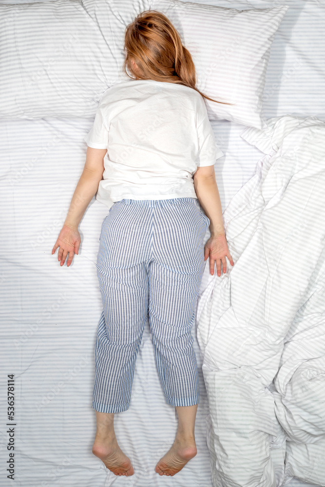 Woman sleeping face down on stomach in bed at home. Deep sleep. Lady