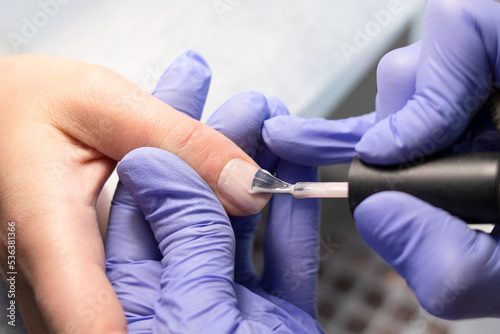 The process of doing a manicure in a spa salon. Manicurist applies nude gel polish on nails in a beauty salon. Applying gel polish. Hand care concept.