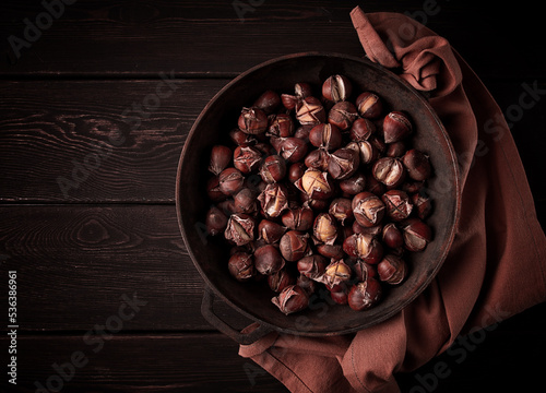 Roasted chestnuts, in an iron pan, wooden table, top view, no people, rustic style,