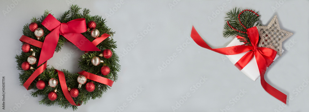 Christmas banner. Christmas wreath and gift box on the gray background. Top view. Copy space.